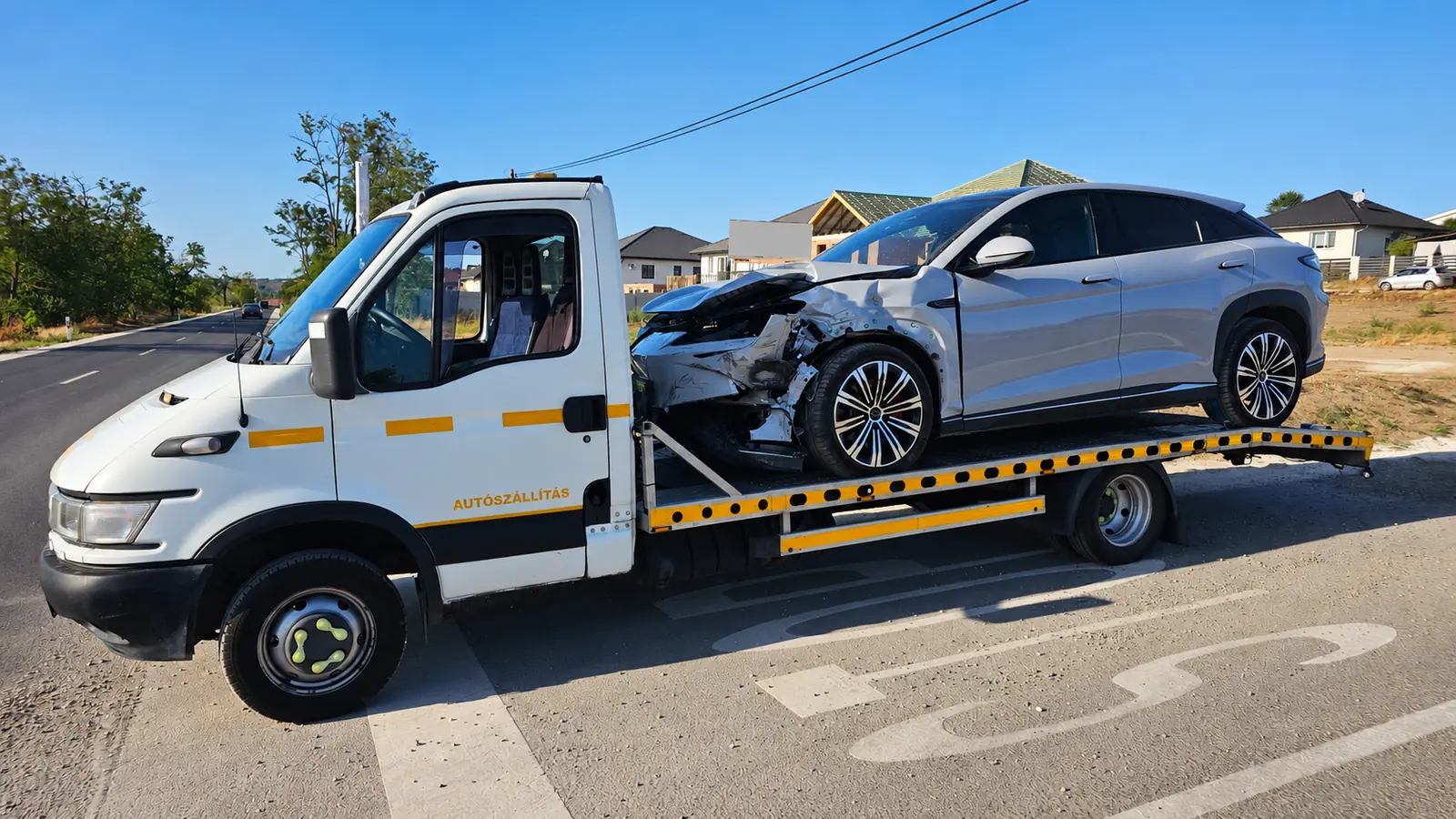 Balesetben sérült elektromos SUV szállítása platós autómentővel
